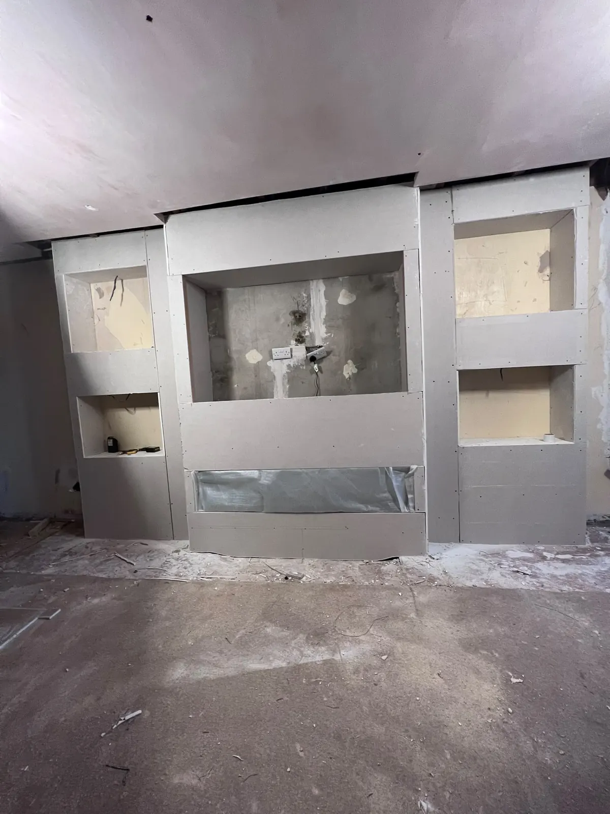 Media wall under construction with stud framing and alcove shelving, Upminster