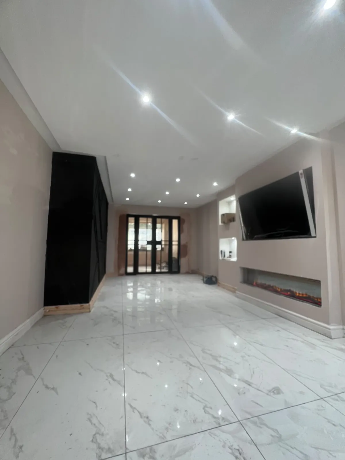 Finished open-plan lounge with fitted black storage and French doors, Upminster